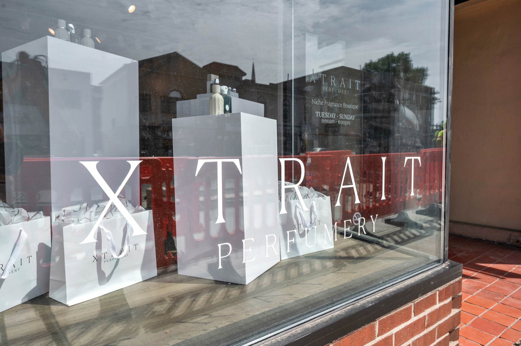 Xtrait Perfumery window display with branded shopping bags